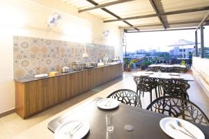 Sanctum Suites Indiranagar Bangalore في بانغالور: مطعم بطاولات وكراسي وكاونتر