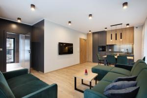 a living room with green couches and a table at PARK APARTAMENTY Krynica Zdrój in Krynica Zdrój