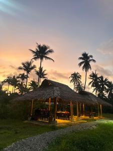 eine Hütte mit Tischen und Palmen bei Sonnenuntergang in der Unterkunft Isola del Sole Villas and Resort in General Luna