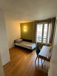 Habitación con cama, escritorio y ventana. en Charming appartment nearby Paris - JO 2024, en Rueil-Malmaison