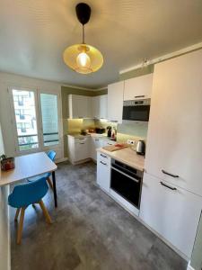 une cuisine avec des placards blancs, une table et une lampe dans l'établissement Charming appartment nearby Paris - JO 2024, à Rueil-Malmaison