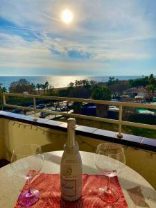 Apart. Pineda de Mar-Sea and mountains views في باينيدا دي مار: زجاجة من النبيذ موضوعة على طاولة مع كأسين من النبيذ