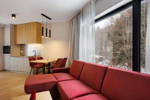 - un salon avec un canapé rouge et une table dans l'établissement PARK APARTAMENTY Krynica Zdrój, à Krynica-Zdrój