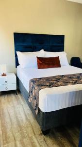 a bedroom with a large bed with a blue headboard at Shiloh Inn in Gaborone