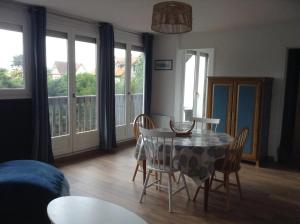 a dining room with a table and chairs and windows at BLUE SEJOUR 14 in Saint-Aubin-sur-Mer