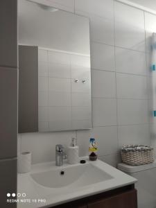 een witte badkamer met een wastafel en een spiegel bij Departamento nuevo y cómodo in Santiago