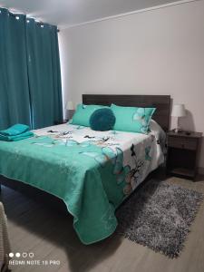 a bedroom with a bed with a green comforter at Departamento nuevo y cómodo in Santiago