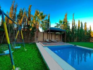 einen Pool in einem Garten mit Bäumen und einem Haus in der Unterkunft agafay villa in Marrakesch