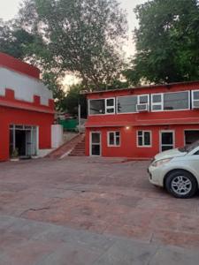 un coche aparcado frente a un edificio rojo en Prince Tourist Lodge,Fatehpur Sikri, en Fatehpur Sīkri