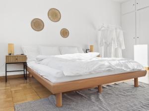 ein weißes Schlafzimmer mit einem Bett mit weißer Bettwäsche in der Unterkunft Alpenzauber Suite für vier in Thun