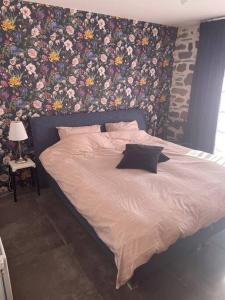 1 cama en un dormitorio con una pared floral en Maison La pierre du lezard, 