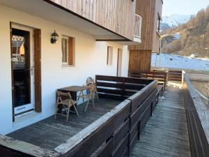 une terrasse en bois avec une table et des chaises dans un bâtiment dans l'établissement Charmant T2 La Foux d’Allos, 5 pers, à Allos