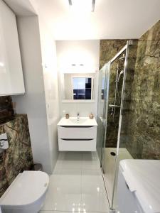 a bathroom with a toilet and a sink and a shower at Słoneczny Apartament Warsaw Spire in Warsaw