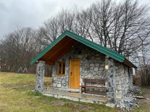 una piccola casa in pietra con tetto verde e porta in legno di Cottages Serdar a Mojkovac