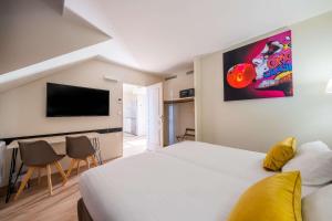 a hotel room with a bed and a flat screen tv at Hôtel Quality Suites Maisons-Laffitte Paris Ouest in Maisons-Laffitte