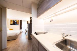 uma cozinha com um lavatório e uma sala de estar em Hôtel Quality Suites Maisons-Laffitte Paris Ouest em Maisons-Laffitte