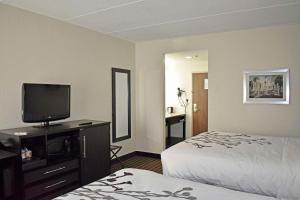 ノックスビルにあるSleep Inn & Suites West Knoxvilleのベッド1台、薄型テレビが備わるホテルルームです。