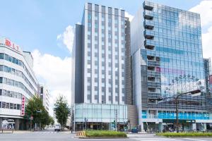 a tall building with glass windows in a city at Comfort Inn Nagoya Sakae in Nagoya
