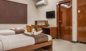 um quarto de hotel com duas camas e uma televisão em Athasri Hotel Infantry Road em Bangalore