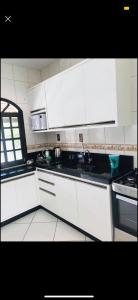 - une cuisine blanche avec des placards blancs et une cuisinière dans l'établissement Casa em Zimbros - DISPONÍVEL CARNAVAL, à Bombinhas