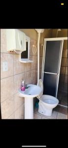 La salle de bains est pourvue d'un lavabo blanc et de toilettes. dans l'établissement Casa em Zimbros - DISPONÍVEL CARNAVAL, à Bombinhas