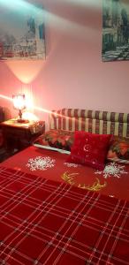 a room with a bed with red sheets and a couch at Guest House Cinderella in Herceg-Novi