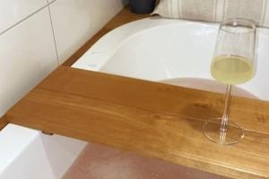 una copa de vino sentada en una bandeja de madera junto a una bañera en Verso la casa mia en Helsinki