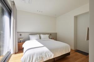1 dormitorio con cama blanca y ventana grande en Mokha forest house, en Jeju