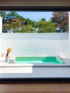 una persona sentada en una bañera en una ventana en Mokha forest house, en Jeju