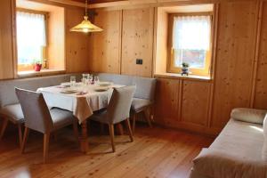 a dining room with a table and chairs and windows at Ciasa Alfri in La Villa