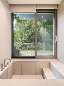 ventana grande en el baño con lavabo en Mokha forest house, en Jeju