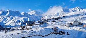 a town on a snowy mountain with snow covered mountains at Segreto apartment 309, 311, 341 in Gudauri