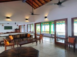 a living room with a couch and chairs and windows at Atulya Lake View - Resort and Spa in Mirissa