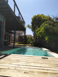 a swimming pool with a wooden deck next to a building at Jbay Holiday Home in Jeffreys Bay