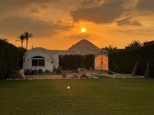 un coucher de soleil avec une montagne en arrière-plan et une balle dans l'herbe dans l'établissement Sahure Pyramid View lnn, au Caire