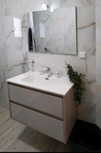 uma casa de banho com um lavatório branco e um espelho. em Boutique lazou em Neochorópoulon