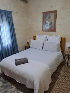 Un dormitorio con una cama blanca con una toalla encima. en De Hoop Guest Farm, en Beaufort West