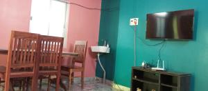 salon z telewizorem, stołem i krzesłami w obiekcie MJ Nakksh w mieście Port Blair