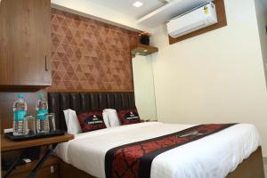 Hotel Yuvika Residency في نافي مومباي: غرفة نوم بسرير وطاولة عليها زجاجات
