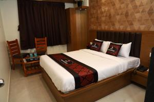 Hotel Yuvika Residency في نافي مومباي: غرفة نوم بسرير وطاولة وكرسي