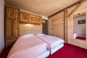 uma cama grande num quarto com paredes de madeira em Hotel Le Grand Tetras em Morzine