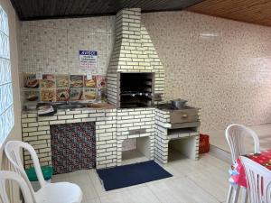 Una cocina con horno de ladrillo con mesa y sillas. en Casa completa, simples e aconchegante em Urubici., en Urubici