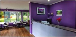 a purple room with a bar with a table and chairs at All Seasons Country Lodge in Taree