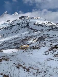ein Haus an der Seite eines schneebedeckten Berges in der Unterkunft სასტუმრო ქორულდი / Hotel Koruldi in Mestia