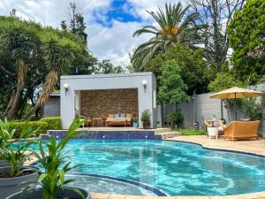 una piscina en un patio trasero con mesa y sillas en Amoris Guesthouse - Sandton en Johannesburgo