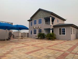 een groot huis met blauwe parasols ervoor bij Family & Friends Apartments in Miocho