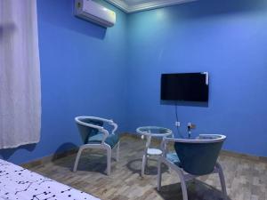 Habitación con 2 sillas y TV en una pared azul. en Family & Friends Apartments en Miocho
