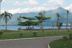 un parque con palmeras y un cuerpo de agua en Pousada Sol do Araçá en São Sebastião