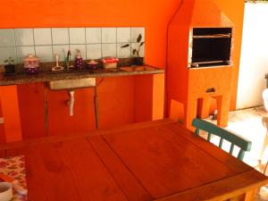 a kitchen with orange walls and a wooden table at Pousada Sol do Araçá in São Sebastião