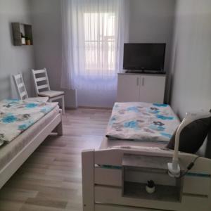a small room with two beds and a flat screen tv at neutal-ferienapartments in Neutal